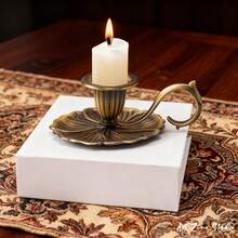 1个优雅复古锌合金烛台，双色金银，圆柱形烛身，带弧形防滑手柄，压花花卉图案，光滑哑光表面，坚固的锌合金结构，耐热易握设计，稳定的蜡烛支撑防止倾倒，点燃时散发温暖的金属光泽，适用于圣诞晚餐、家庭聚会、秋季露营、节日礼物等场合，兼具复古优雅和实用功能。