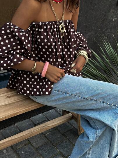 Damestop met stippenprint, off-shoulder model en pofmouwen, een modieuze zomerse resortstijl.