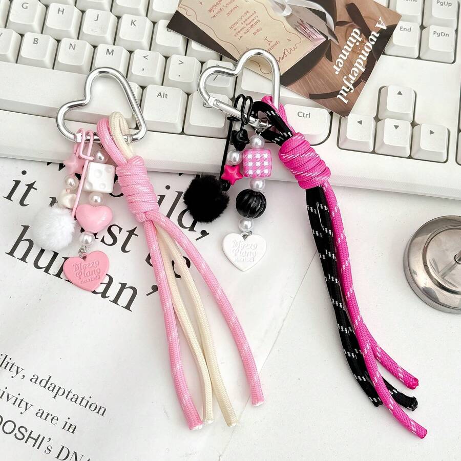 Questo portachiavi a forma di cuore è realizzato in corda intrecciata resistente con un design personalizzato. È un accessorio multifunzionale che può essere appeso a borse e bagagli per aggiungere un tocco di moda e può anche essere un ottimo piccolo regalo per uso quotidiano. - Multicolore - Visualizzare 1