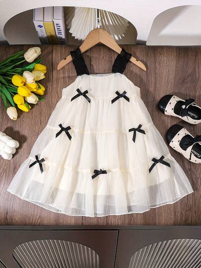 女童甜美黑色吊带蝴蝶结杏色连衣裙，可爱甜美风格，宽松舒适，适合休闲外出、户外玩耍、亲子活动、节日、假期等场合。