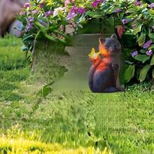 这是一款亚克力材质的猫形户外装饰灯，无需用电。卡通猫咪造型，质感如石头般柔软，立于草坪之上，一只爪子“捧着”一盏暖光灯笼。造型俏皮可爱，与图片中木质露台和绿植花园的休闲环境相得益彰，为庭院增添了一份温馨愉悦的氛围。 - 彩色 - 查看 2