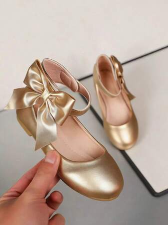 Bailarinas infantiles con correa de tobillo y decoración de lazo, que muestran un estilo de zapato elegante