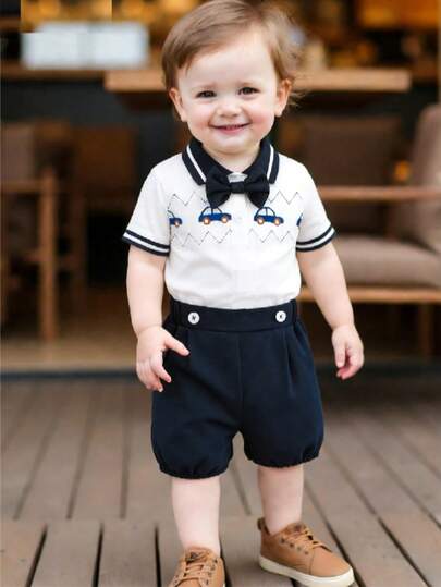 2 piezas Conjunto de niño pequeño de camisa de manga corta con estampado de coche de dibujos animados y rayas, corbata de moño desmontable, y pantalones cortos casuales de caballero