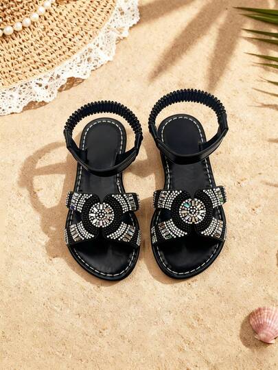 一双女童凉鞋，黑色鞋底，饰以钻石花朵，露趾平底，舒适闪亮，华丽甜美，是夏季派对的完美之选