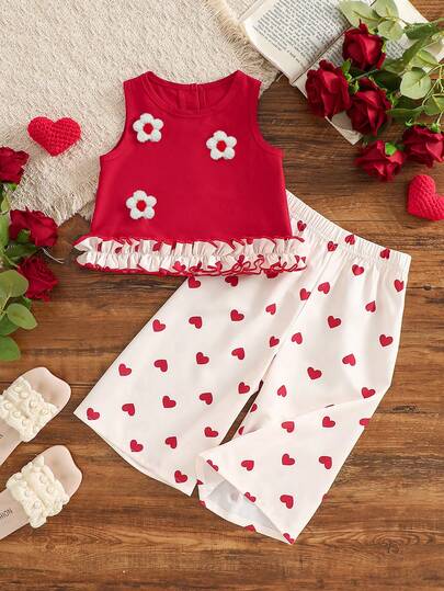 两件套女宝宝夏季套装，活泼可爱。上衣为无袖露脐背心，饰有3D白色花朵，荷叶边下摆设计，增添俏皮层次感。下装为印花红色爱心图案的阔腿裤，宽松舒适，方便穿着，是度假和户外活动的理想之选。