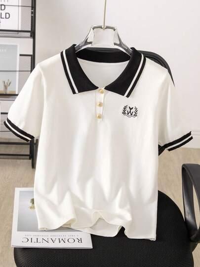 Áo polo trắng mới, thiết kế cổ đen, viền sọc trắng, phối đen trắng, cúc vàng, họa tiết thêu đen ở ngực trái, dáng regular fit, phù hợp cho mặc thường ngày.