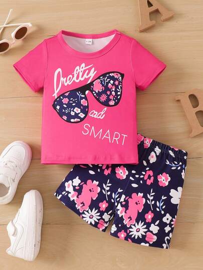 Bộ đồ mùa hè năng động cho bé gái gồm kính râm và áo phông in chữ cùng quần short họa tiết hoa, thích hợp cho mùa xuân/hè.