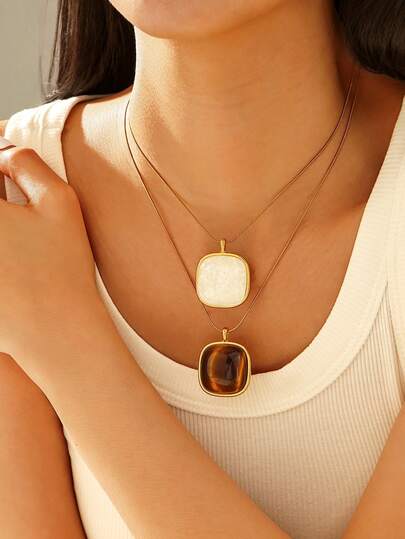 1条18K镀金不锈钢项链，长度可调节，方形吊坠镶嵌白色宝石或虎眼石，适合女性佩戴或作为礼物。