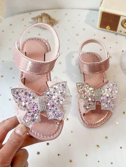 Một đôi sandal đế bằng hở mũi chống trượt kiểu ba lê dành cho bé gái, kiểu dáng mới năm 2026, được trang trí bằng vải lưới đính sequin và nơ, thích hợp cho biểu diễn sân khấu / phối cùng váy sinh nhật / dự tiệc mùa hè.