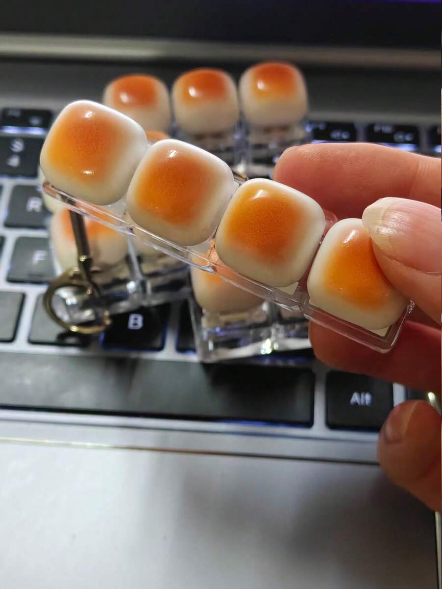 1个焦糖面包造型钥匙扣，可作为减压玩具、机械键盘测试器、钥匙扣、桌面装饰、手机挂饰和创意可伸缩玩具。