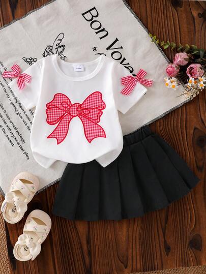 2pcs Baby Girl Fashionable Elegant Plaid Bow Decor Round Neck Short Sleeve T-Shirt Top And Solid Black Pleated Mini Skirt Set