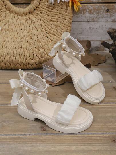 1双白色幼儿/儿童厚底时尚凉鞋，带荷叶边网眼绑带、蝴蝶结珍珠装饰、魔术贴搭扣，简约圆头设计，舒适可爱的罗马风格沙滩凉鞋，适合3-15岁女孩，春夏款。