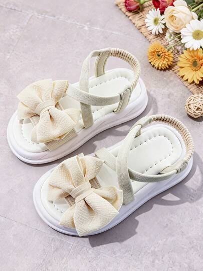 1双时尚儿童凉鞋，女童米色平底凉鞋，蝴蝶结装饰，防滑鞋底，套穿式设计，适合宴会、聚会、派对、婚礼、度假等场合。