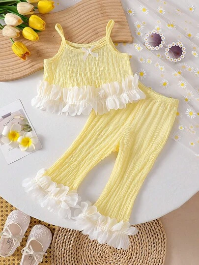 女婴可爱纯色无袖蝴蝶结装饰吊带背心搭配松紧腰碎花裤两件套，时尚舒适的公主风休闲套装，适合春夏日常穿着和外出活动。