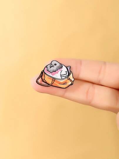 1枚可爱俏皮鹦鹉珐琅胸针 - 一只脸颊泛红的鹦鹉躲在橙色斜挎包里，粉色脸颊细节，黑色轮廓，男女皆宜的翻领胸针，适合爱鸟人士和可爱风爱好者，日常佩戴或作为礼物，充满奇思妙想的鸟类主题时尚配饰。