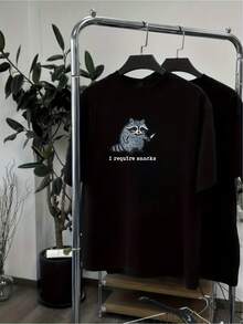 Camiseta Unisex con Estampado Divertido de Mapache Necesito Snacks Casual y Original para Amantes de los Animales Perfecta para Llevar la Cultura Pop y Estilo Urbano a las Calles Fabricada en Algodón de Alta Calidad Ideal para Regalos Cómicos y Únicos - Negro - Ver 1