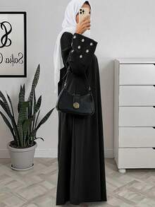 一件女士斋月长袍 - 黑色长裙，袖子上饰有白色花卉刺绣，圆领长袖，采用柔软梭织面料制成，优雅的伊斯兰服饰，适合开斋节聚会和春季庆祝活动。 - 黑色 - 查看 2