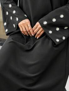 一件女士斋月长袍 - 黑色长裙，袖子上饰有白色花卉刺绣，圆领长袖，采用柔软梭织面料制成，优雅的伊斯兰服饰，适合开斋节聚会和春季庆祝活动。 - 黑色 - 查看 4