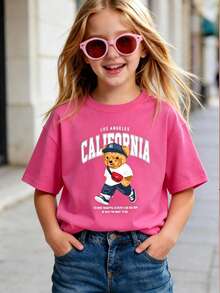 Esta camiseta de manga corta para niñas presenta un diseño gráfico único de oso, combinado con un cuello redondo suave, lo que la convierte en una camiseta rosa cómoda e informal. - Rosa Fucsia - Ver 1