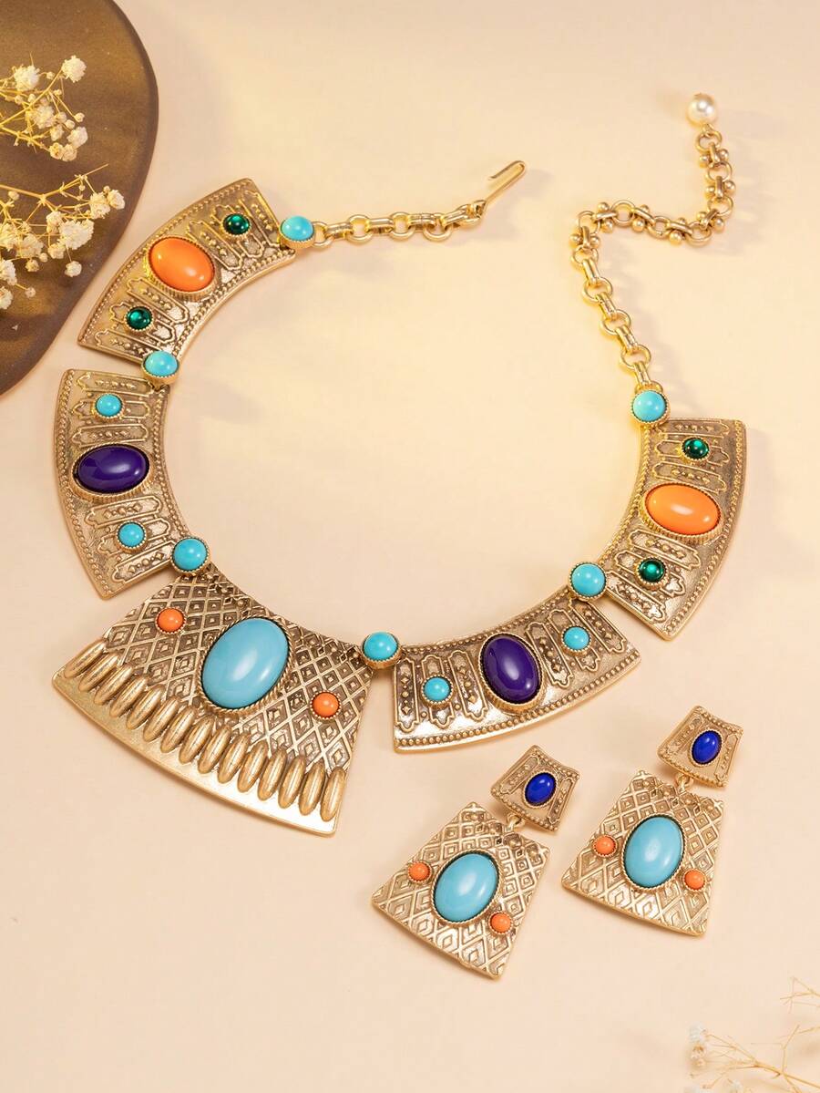 这是一套波西米亚风格的首饰套装，包含一条项链和一对耳环。首饰以金色金属底座制成，镶嵌着绿松石、橙色和紫色宝石或仿制宝石。设计融合了三角形等几何元素，展现出复古奢华的风格，非常适合搭配波西米亚风和度假风的服装，增添独特的魅力。 - 彩色 - 查看 1