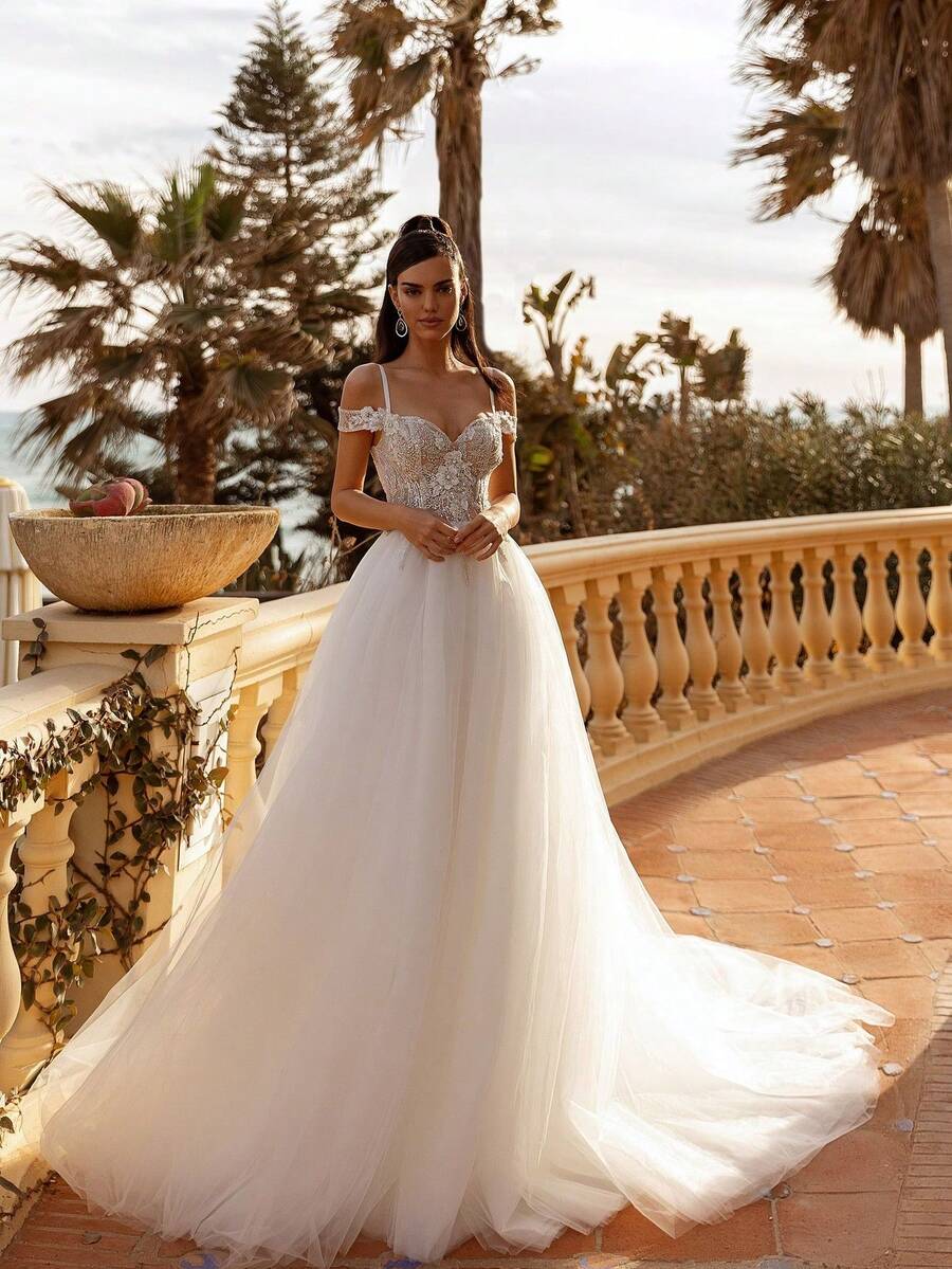 Enchanting Sweetheart Neckline Spaghetti Strap Wedding Dress With Daring Low Back And 3D Floral Accents – A Sophisticated Ivory A-Line Floor-Length Gown Featuring Delicate Botanicals, Flowing Silhouette, And Elegant Details, Perfect For Wedding Ceremonies, Holiday Events Including Christmas Galas And Halloween Parties, Formal Balls, Prom Nights, Birthday Celebrations, Anniversary Dinners, Bridal Showers, Honeymoon Getaways, Evening Soirées, Graduation Banquets, Homecoming Dances, Cocktail Receptions, And As A Stunning Guest Outfit For Special Occasions. This Dreamy A-Line Gown Combines A Flattering Sweetheart Neckline With Dainty Straps, Captivating Floral Embellishments, And Alluring Open Back Design For A Truly Magical Look. - 白色 - 查看 1