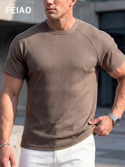 男士复古硬币图案罗纹T恤，触感丝滑柔顺，竖条纹纹理更添层次感。修身剪裁凸显肌肉线条，圆领和插肩袖设计打造宽阔挺拔的肩部轮廓。适合运动或休闲穿着，展现干练利落的形象。