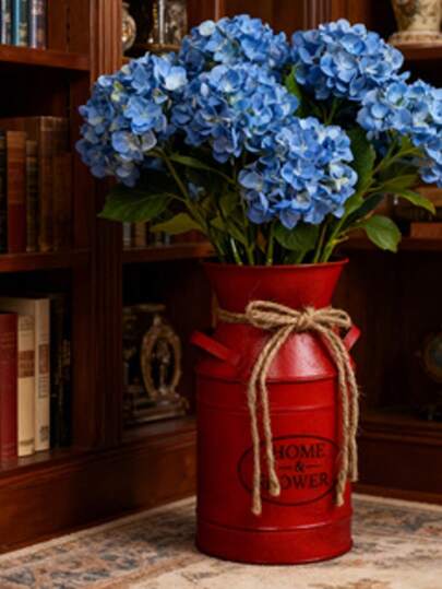 这款做旧红色铁艺花瓶，瓶身饰以天然黄麻绳，印有复古“HOME & FLOWERS”标语，散发着温暖的美式乡村气息，适合复古美式、田园风、节日装饰等场景。插入百合花，即可打造优雅神圣的桌面焦点；或插上冬青枝，营造节日氛围，适用于各种温馨场景。