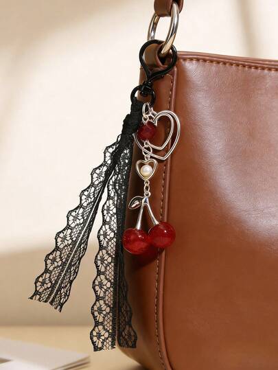 这款复古甜美的红色亮面樱桃造型包包挂饰/钥匙扣，饰以精致的蕾丝缎带，搭配心形挂钩，打造出浪漫优雅的包包挂饰。亮面樱桃图案与黑色蕾丝相得益彰，更添一丝柔美气质。适用于钥匙链、背包装饰等多种用途。