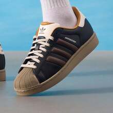 男女通用低帮经典帆布鞋，贝壳头系列，简约线条设计，舒适休闲鞋，适合日常穿着、通勤和学生穿着 JP9187 - 黑色/棕色/奇妙白 - 查看 8