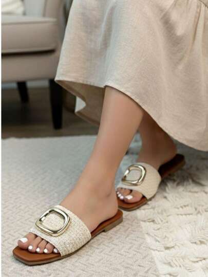 Sandalias planas de mujer con detalle de tejido y hebilla dorada que aporta un toque elegante y moderno.