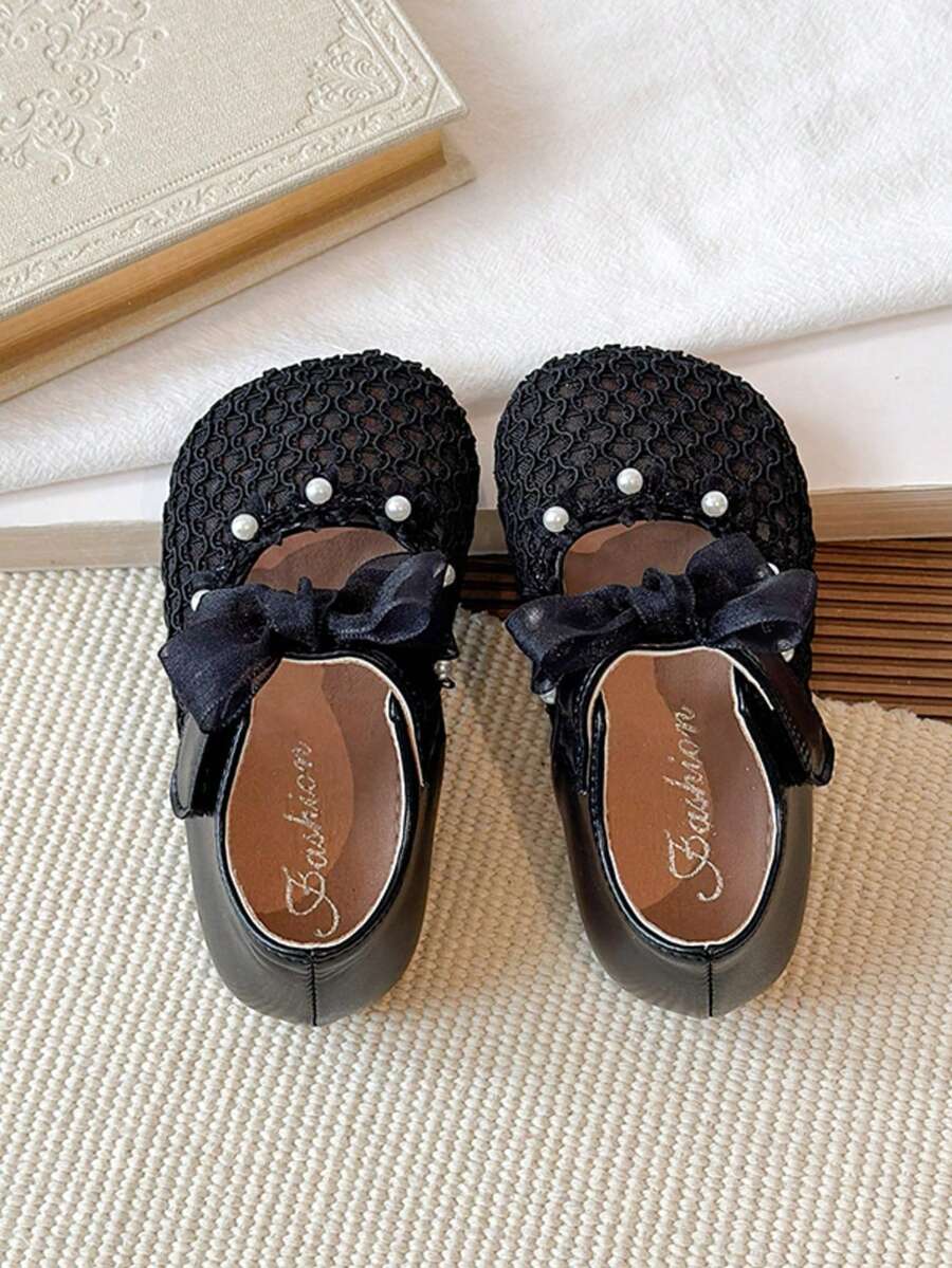 1双黑色蝴蝶结镂空可爱时尚珍珠设计软底防滑平底婴幼儿鞋，适合春、夏、秋、冬四季穿着。