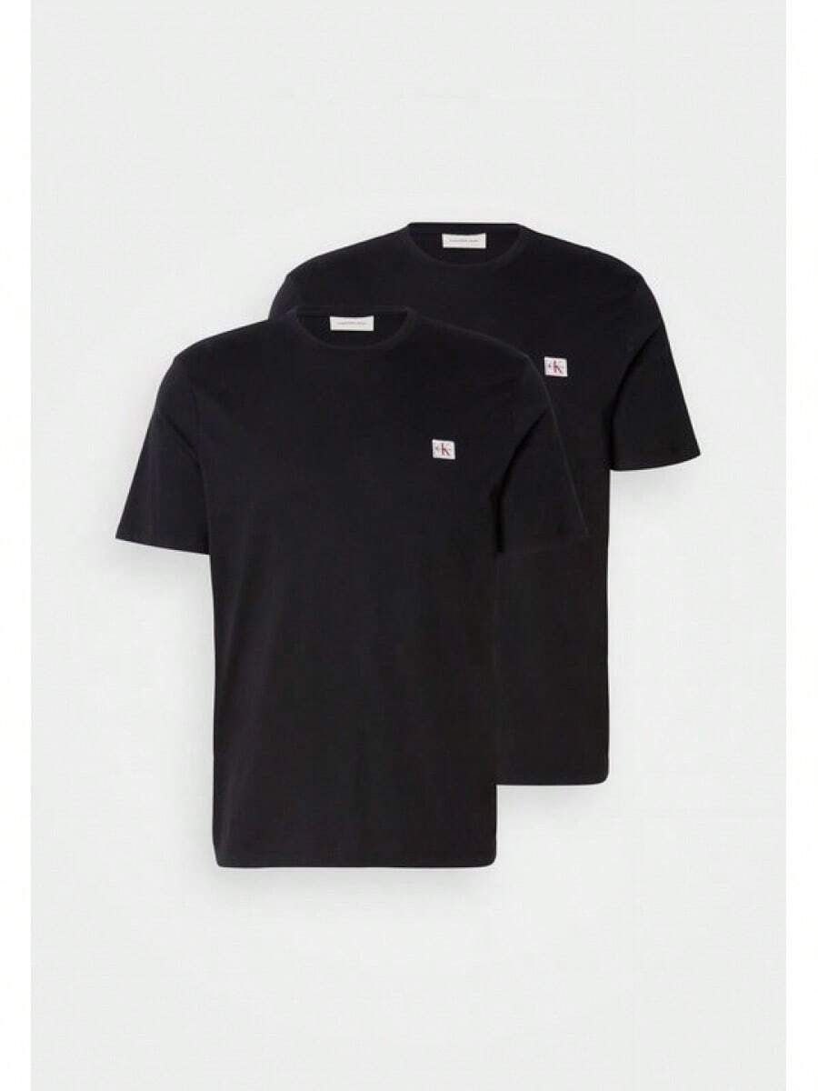 Czarny bawełniany T-shirt z małym logo w połączeniu z ciemnymi jeansami. Model ma na sobie czarny kapelusz i czarne buty, stoi na jasnej podłodze. Męski T-shirt z krótkim rękawem. - Czarne - Zobacz 1