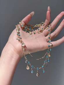 两件套蓝色水钻贝壳项链和手链，饰以闪亮的蓝色水钻和精致的贝壳设计，打造出轻盈奢华、别具一格的优雅外观。 - 彩色 - 查看 2