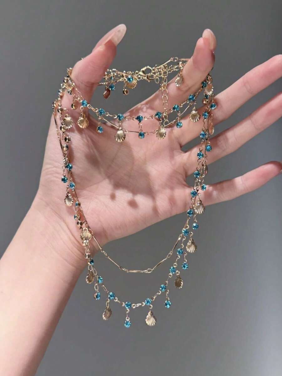 两件套蓝色水钻贝壳项链和手链，饰以闪亮的蓝色水钻和精致的贝壳设计，打造出轻盈奢华、别具一格的优雅外观。 - 彩色 - 查看 1