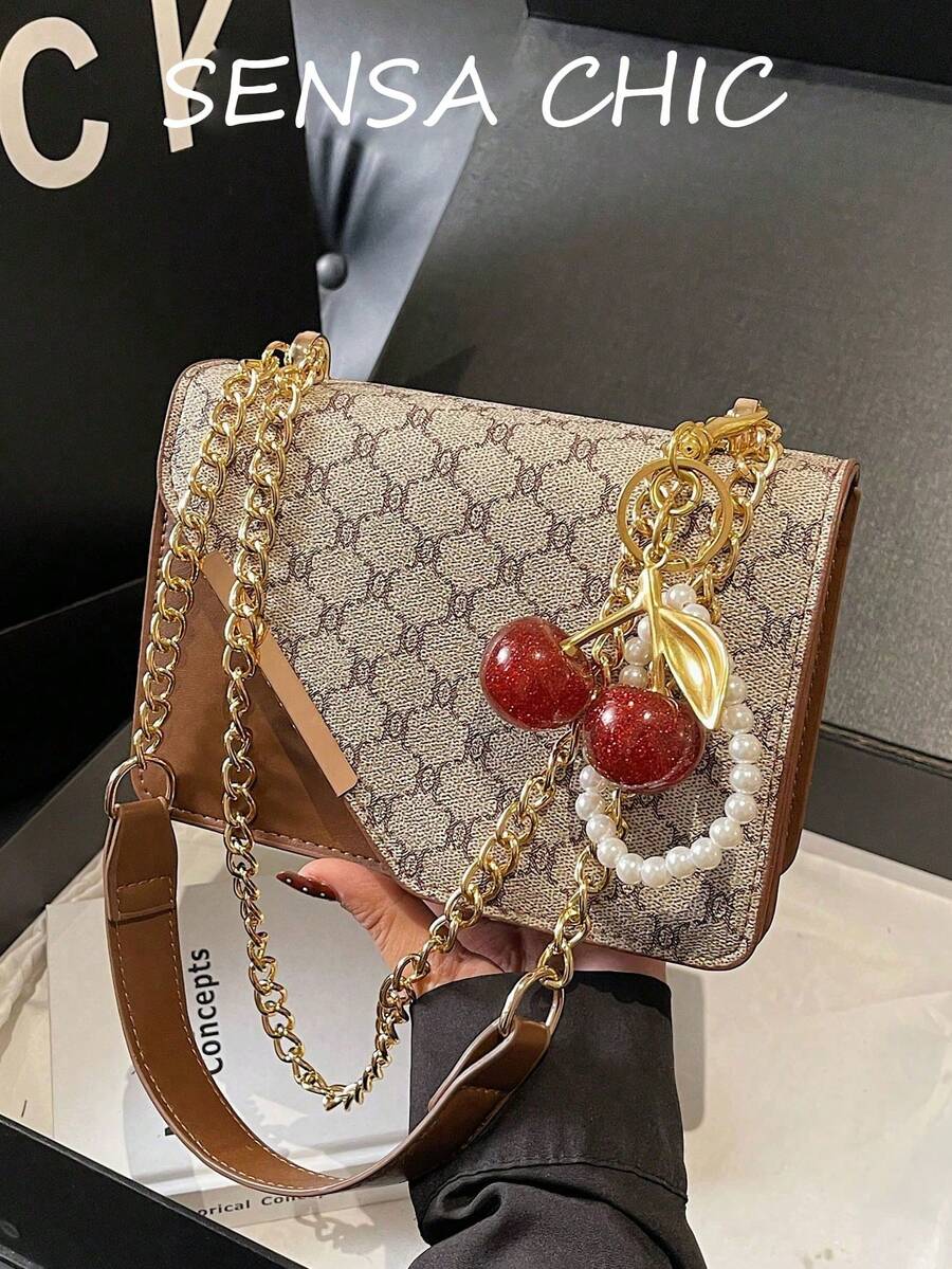 Chiếc túi đeo vai thời trang và đa năng này có thiết kế màu cà phê tương phản, được tô điểm bằng mặt dây chuyền ngọc trai và quả anh đào. Túi có hai khóa nam châm và một dây xích kim loại phía trên. Chiếc túi vuông nhỏ gọn này có thể đeo trên vai, đeo chéo hoặc xách tay, và có thể đựng những vật dụng cần thiết hàng ngày như son môi, chìa khóa và mỹ phẩm. Thích hợp cho các bạn nữ sử dụng khi đi làm, đi chơi, mua sắm, hẹn hò và các dịp hàng ngày. - Cà phê - Xem 1