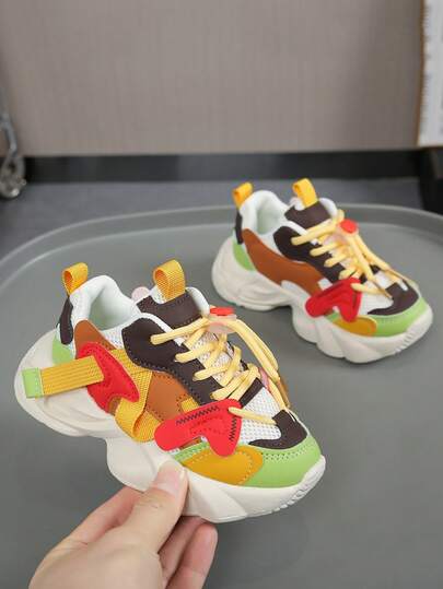 一双儿童运动鞋。这款儿童厚底运动鞋采用醒目的撞色设计，融合了红色、绿色、棕色、黄色等多种色彩层次。透气网布搭配柔软皮革鞋面，兼顾透气性和支撑性，让孩子全天穿着舒适。无鞋带锁扣设计，方便孩子自行调节松紧度，穿着舒适稳固。加厚防滑外底提供缓冲和抓地力，有效吸收行走或跑步时的冲击力，保护孩子的脚踝。加固鞋头提供全方位保护，有效抵御磕碰。