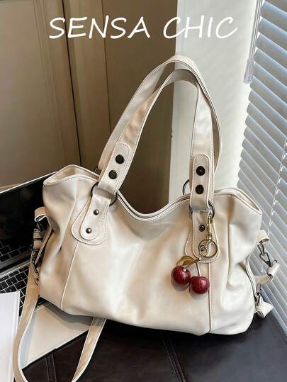 这是一款女士大容量纯色手提包，饰有红色樱桃吊坠。这款包采用顺滑拉链封口，配有双提手和可调节长肩带，方便您肩背、手提或斜挎。