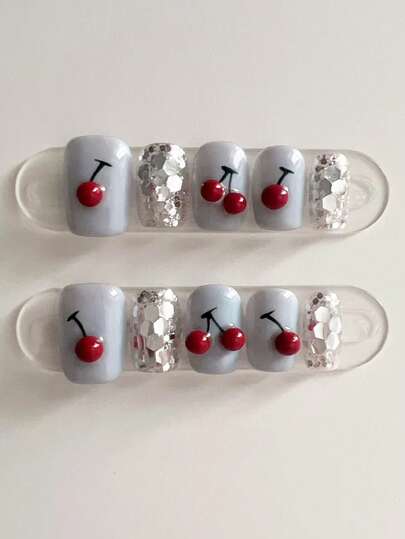 这款10片装美甲贴以浅蓝色为主色调，充满俏皮甜美和清爽魅力。部分指甲饰以鲜艳的樱桃图案，并点缀银色亮片，既吸睛又时尚。柔和的浅蓝色底色搭配醒目的装饰元素，使其更加独特，适合休闲场合。适合女士和女孩在日常出行、休闲聚会和各个季节的休闲时光中使用。手工制作的按压式美甲贴。