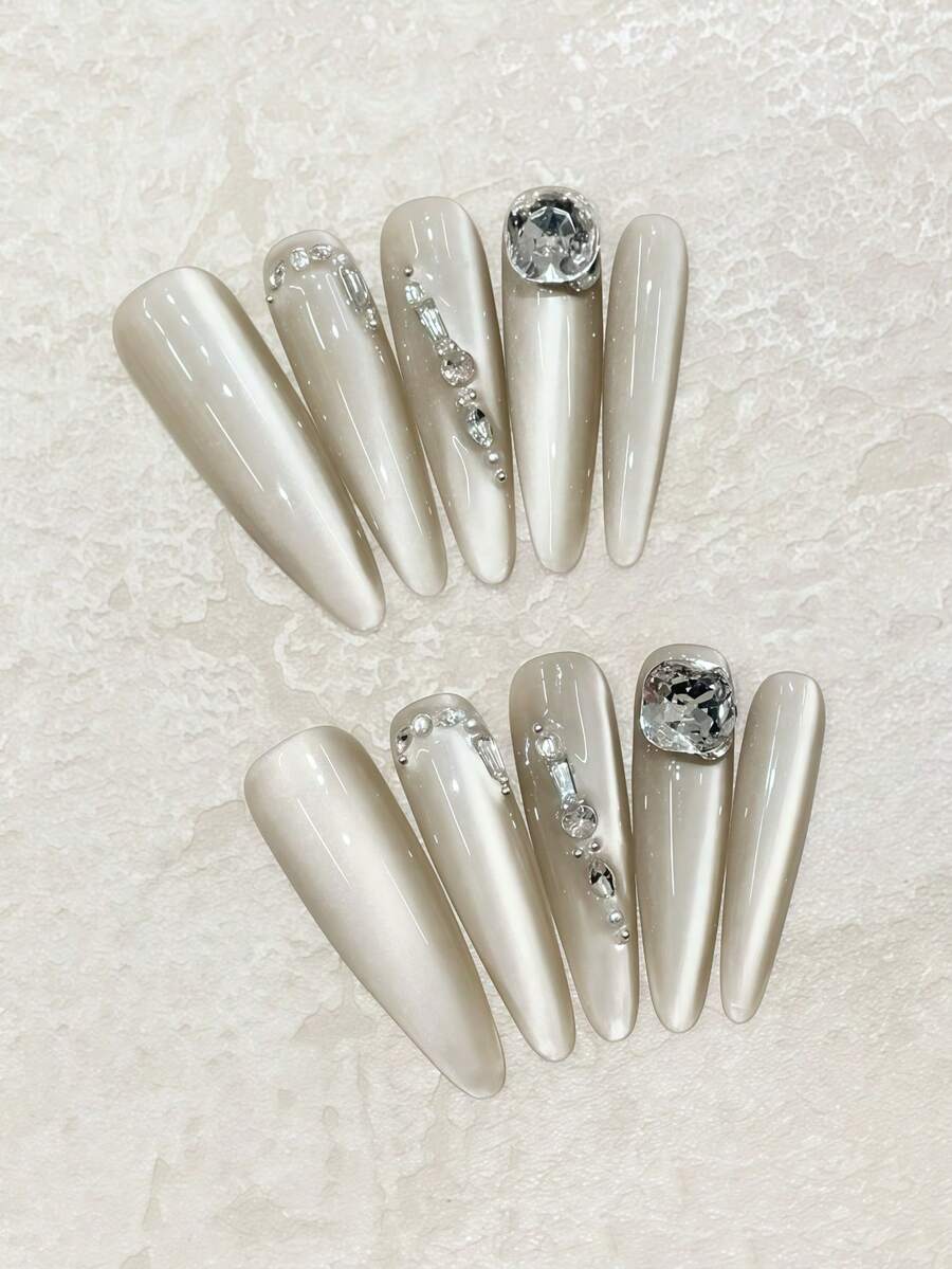 ¡Lujo a la punta de tus dedos! Juego de 10 uñas largas y puntiagudas hechas a mano en gris con destellos laterales de ojo de gato y acentos de cristal de imitación cuadrado K9. Lleno de una sensación lujosa y de alta gama. Perfecto para citas, uso diario o reuniones con amigos. Puede ser un regalo para amigos. Juego reutilizable de uñas postizas hechas a mano con una pieza de pegamento de gelatina y una lima de uñas en miniatura.