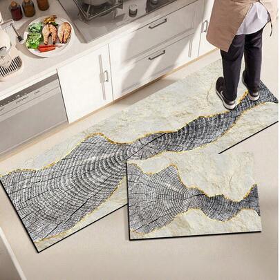 1 tấm thảm bếp bằng gel silica, với họa tiết vân gỗ sống động và những đường cong vàng óng ánh trên nền màu be và xám đậm, tạo nên một tác phẩm nghệ thuật hiện đại tự nhiên nhưng sang trọng. Tấm thảm bếp thời trang và thoải mái, có khả năng giảm chấn và chống mỏi. Bề mặt được làm bằng chất liệu vải, lớp giữa là chất liệu xốp thấm hút, và lớp dưới là chất liệu cao su, giúp dễ dàng vệ sinh và bền bỉ.