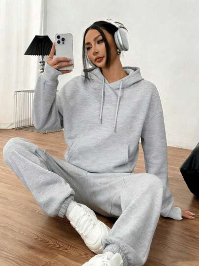 Conjunto informal de sudadera gris con capucha de manga larga y pantalón deportivo para mujer con bolsillo con cordón ajustable. Estilo urbano de invierno.