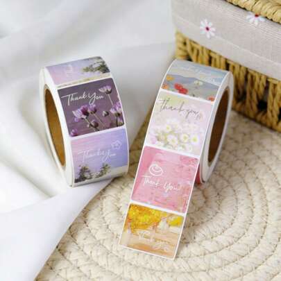 Un rotolo di piccoli e freschi adesivi di ringraziamento con paesaggi - etichette adesive quadrate per il trasporto di e-commerce, ordini di piccole imprese e buste sigillate - adesivi per sigillatura