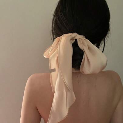 1pc Solid Color Satin Headband, This Is A Styling Image Showcasing A Satin Headband Scarf Hair Accessory. The Image Presents The Back View Of A Woman, Who Has Tied Her Dark Hair Into A Low Bun, Using A Light Peach Satin Headband Tied Into A Bow. The Long Trailing Ends Of The Headband Are Clearly Visible, Providing A Graceful And Lustrous Effect. The Overall Look Is Minimalist Yet Atmospheric, Suitable For Pairing With Light Mature, French, Or Gentle Style Outfits, Serving As A Small Detail To Elevate The Overall Aesthetic.