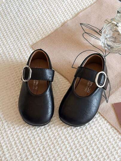 1 đôi giày da trẻ em màu đen mũi tròn có khóa kim loại trang trí, đế mềm.