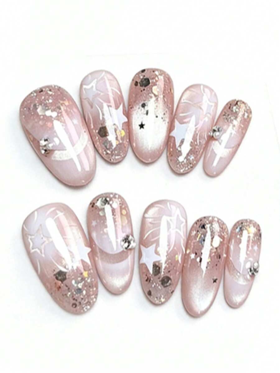 这款美甲套装包含10片指甲油，名为“粉红星光金雾”。它巧妙融合了半透明粉色和猫眼光泽，并以手绘白色星星、亮片和水钻图案点缀。亮泽的质地更凸显了梦幻般的光泽，是喜爱甜美低调美甲人士的完美之选。 - 淺粉色 - 查看 1