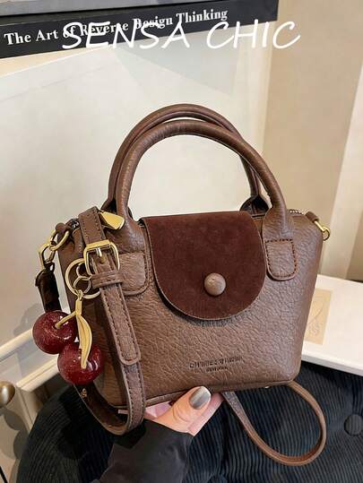 This Women's Handbag Is Made Of Square-Shaped Coffee-Colored PU Leather Material, Combining Aesthetics And Versatile Style. It Features Smooth Metal Zippers, Dual Top Handles, Letter Decoration, And A Red Cherry Pendant. The Body Has A Textured Pebbled Pattern And An Adjustable Long Shoulder Strap For Easy Shoulder Carrying.