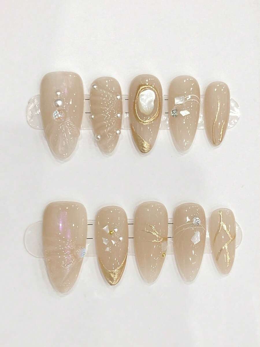 10片纯手工制作的中号杏仁形美甲贴片，以杏色为底，饰以金线、珍珠母贝小钻以及立体贝壳图案，点缀着小珍珠和小钻，呈现出精致低调的优雅气质。温柔优雅的可爱美甲，适合女士和女孩在春夏秋冬的各种节日、派对和日常生活中使用。 - 杏色 - 查看 1