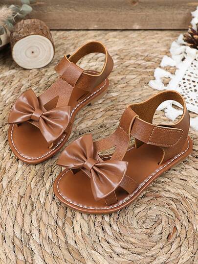1双棕色加大码女童平底凉鞋，纯色PU鞋带，饰有大蝴蝶结，魔术贴闭合，露趾设计，奢华时尚罗马凉鞋，适合3-15岁女孩，休闲、派对、旅行皆宜，2026春夏款