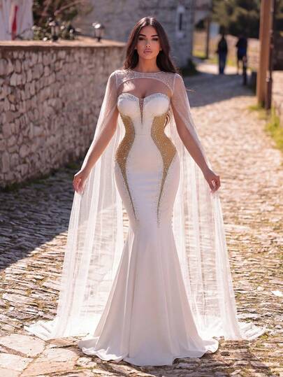 Faeriesty 这款华丽的美人鱼婚纱，饰以闪亮水钻，搭配轻盈的薄纱披肩和飘逸的及地长裙——是婚礼、正式晚宴、颁奖典礼和红毯活动的理想之选。白色