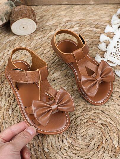 1双棕色加大码女童平底凉鞋，纯色PU鞋带，饰有大蝴蝶结，魔术贴闭合，露趾设计，奢华时尚罗马凉鞋，适合3-15岁女孩，休闲、派对、旅行皆宜，2026春夏款